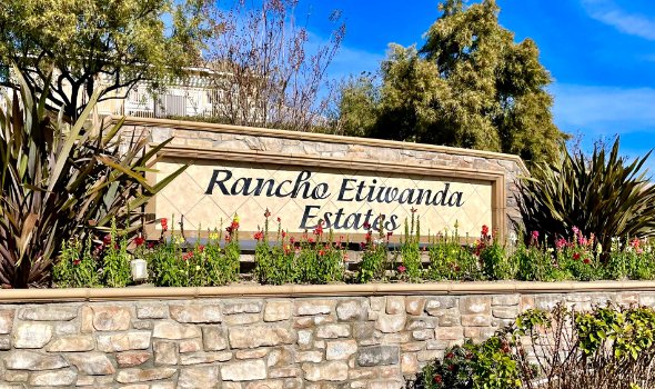 Rancho Etiwanda Estates signage in a stone wall with lots of plant and flowers around | Rancho Etiwanda Estates Homes For Sale | Alvin Tapia