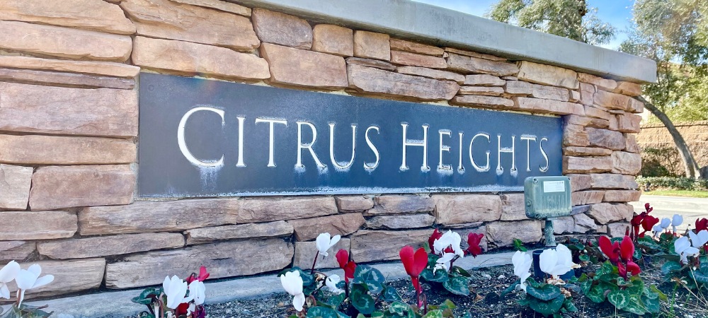 Brick wall with Citrus Heights signage and red and white flowering plants-Homes For Sale in Citrus Heights-Featured Image-Alvin Tapia