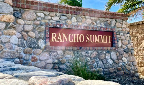 Colored stone wall with Rancho Summit name and palm tress in the background | rancho summit homes for sale rancho cucamonga | Alvin Tapia