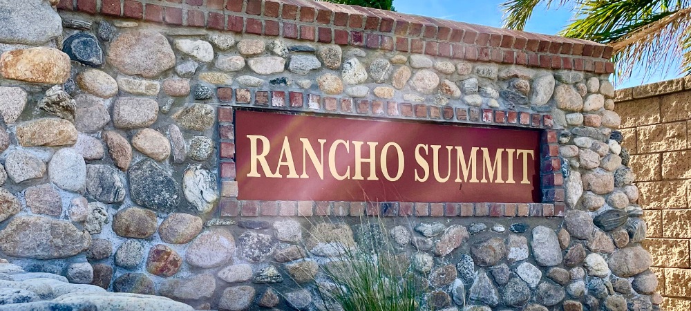 Colored stone wall with Rancho Summit name and palm tress in the background-Rancho Summit Homes For Sale-Featured Image-Alvin Tapia