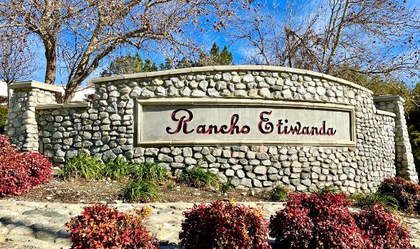 Stone wall with Rancho Etiwanda name with red font color tall trees in the background | homes for sale rancho cucamonga etiwanda | Alvin Tapia